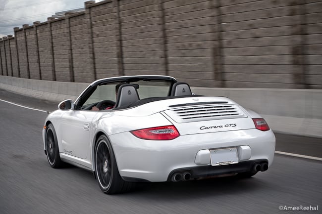 White 2011 Porsche 911 Carrera GTS Cabriolet rear view driving on the road